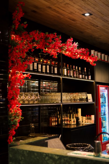 Barra con la estantería de bebidas y flores rojas