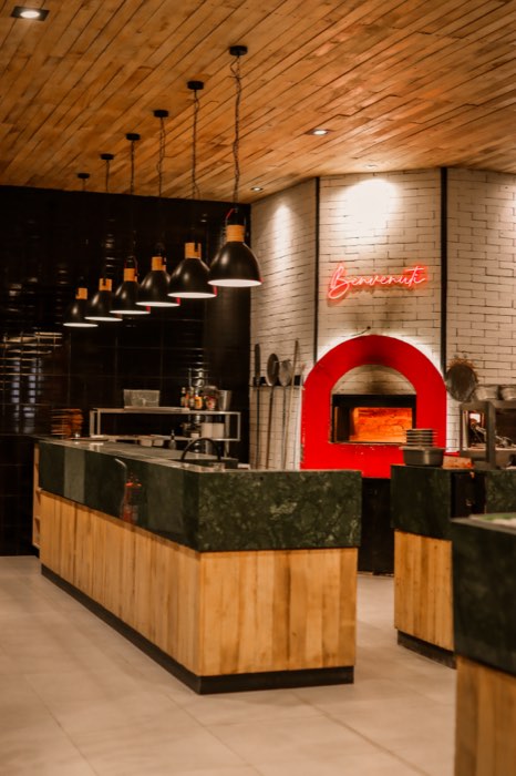 Horno de pizza rojo con el cartel de neón Benvenuti