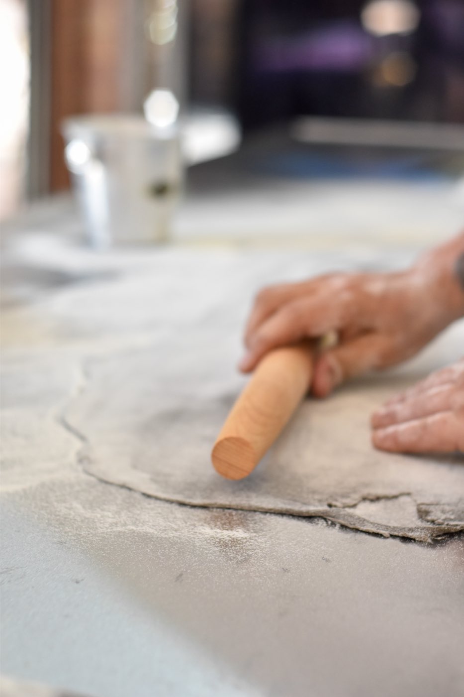 Manos amasando la pasta con palote sobre la mesa de trabajo